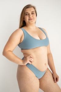 bodya błękitna góra stroju kąpielowego na modelce – szerokie ramiączka, sportowy fason, głęboki dekolt, widok z przodu